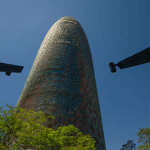 Modern Barcelona tower shot from below, featuring sleek architecture against clear blue sky.